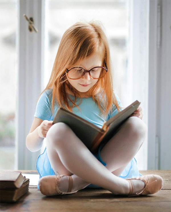 little girl in glasses with learning difficulties like Dysgraphia, ADHD is reading a book because Dysgraphia is not a barrier to success