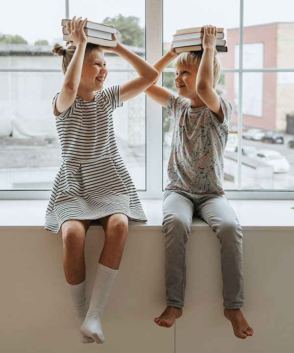 Support space for people with learning differences, two kids sitting in window with books on their heads.